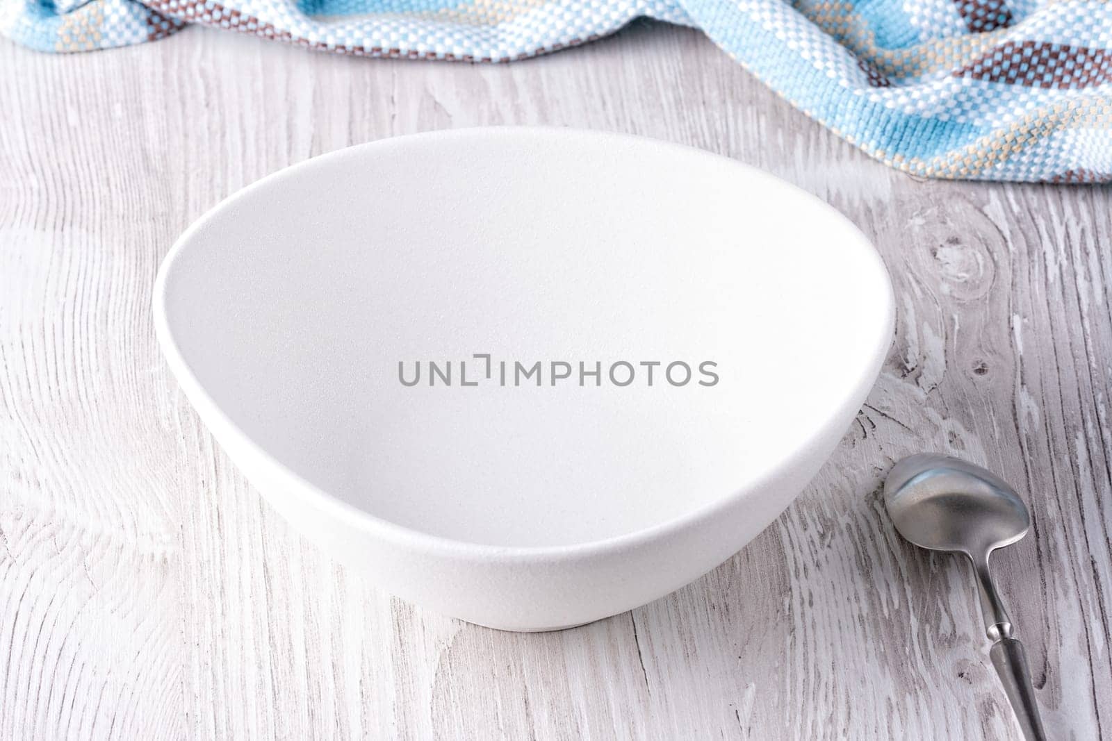 Empty bowl and spoon on wooden table.