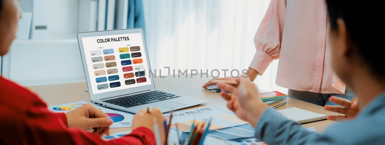 A portrait of creativity graphic designer team select appropriate color for the project by using laptop on table with equipment and designing tool scatter around at modern office. Closeup. Variegated.