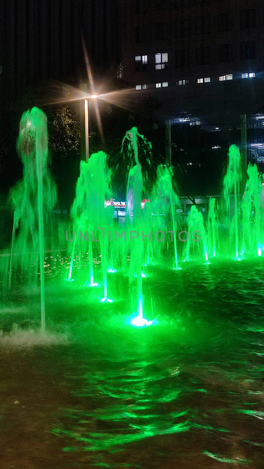 fountain at night in the city, green water color. High quality photo