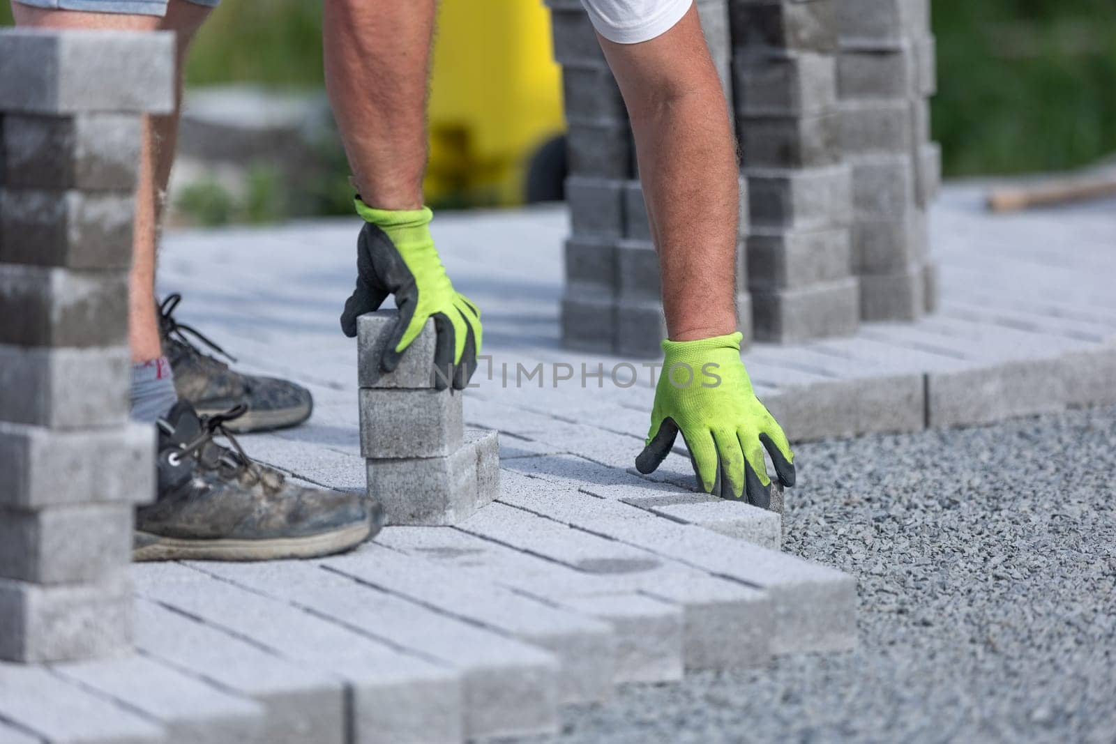 Worker doing new interlocking paving sidewalk made from concrete blocks by Kadula