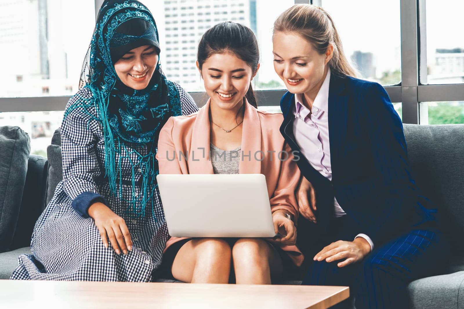 Multicultural working group. Team of businesswomen of different ethnicity, Caucasian, Asian and Arabic working together with laptop computer at office workplace. Multiethnic teamwork concept. uds