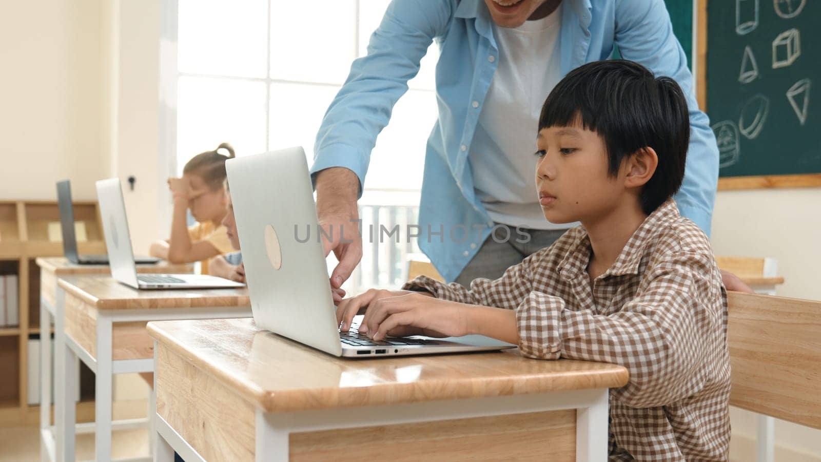 Caucasian teacher helping asian student coding engineering prompt while diverse student using software generated AI. Smart happy attractive children sitting and programing system. Education. Pedagogy.