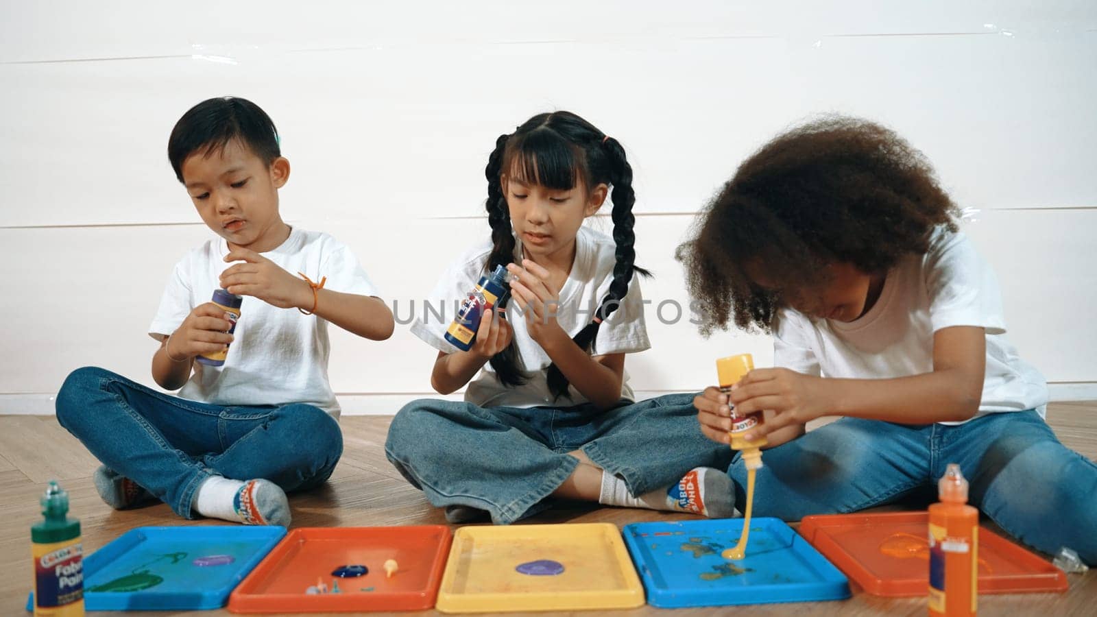 Group of diverse young student mixing color while sitting together. Happy multicultural children prepared mixed to playing and creating new artwork at art lesson. Creative activity concept. Erudition.