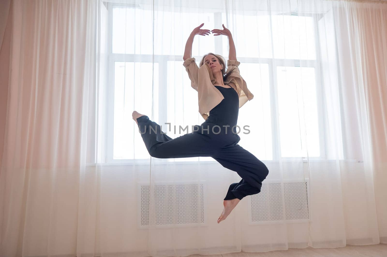 Caucasian woman dances contemporary in ballet class. Dancer in a jump