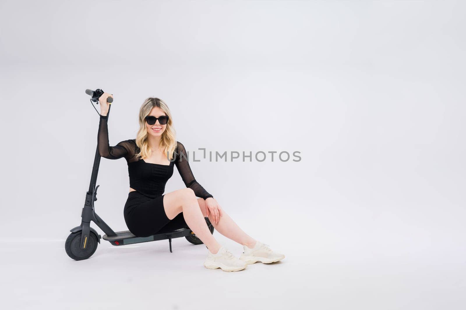 Full body young woman riding an electric scooter isolated studio portrait. Lifestyle concept