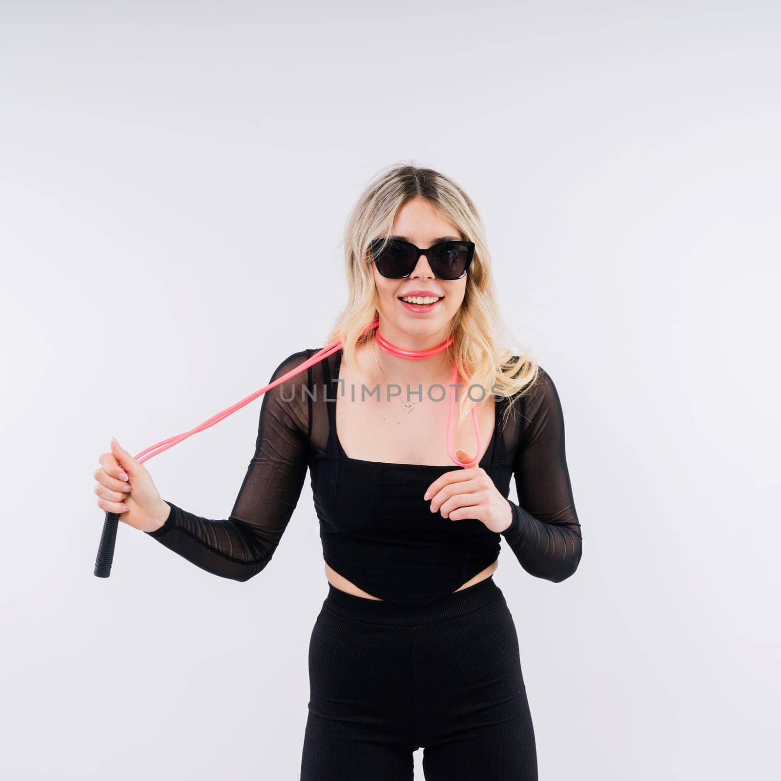 Beautiful fitness female posing on studio background with jumping rope by Zelenin