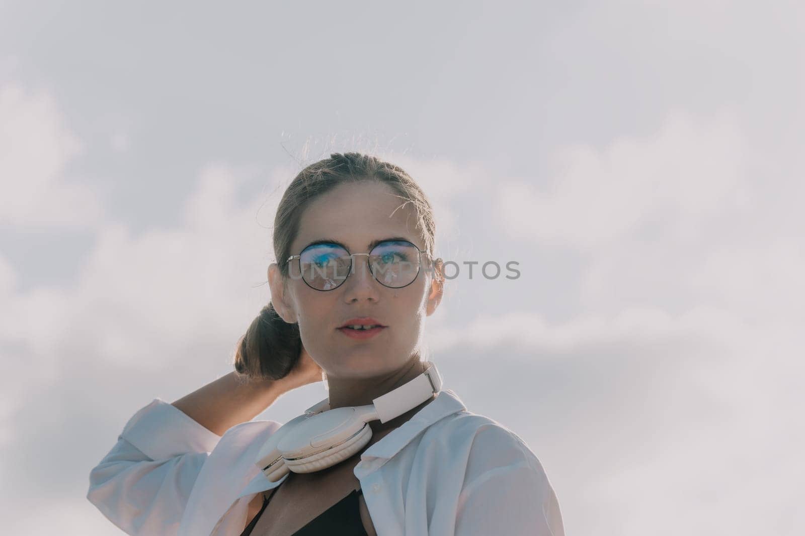 Digital nomad, woman in the hat, a business woman with a laptop sits on the rocks by the sea during sunset, makes a business transaction online from a distance. Freelance, remote work on vacation.