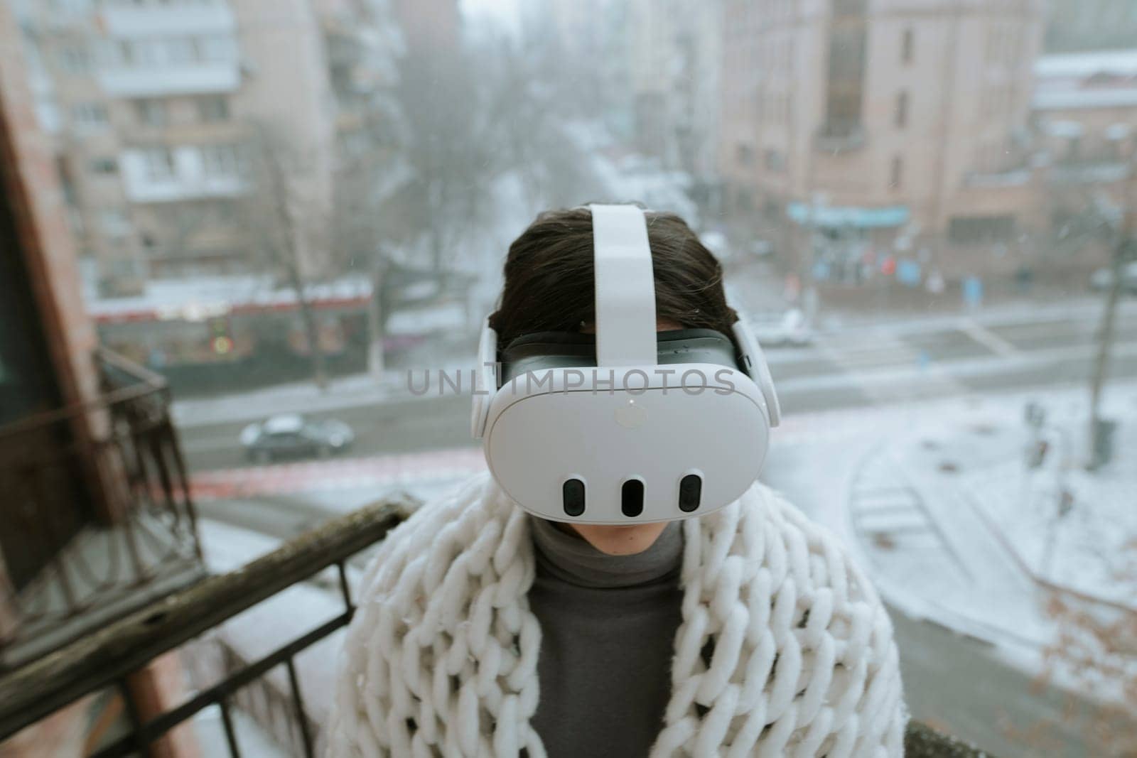 On the balcony in winter, a girl embraces virtual reality adventures with a headset. High quality photo