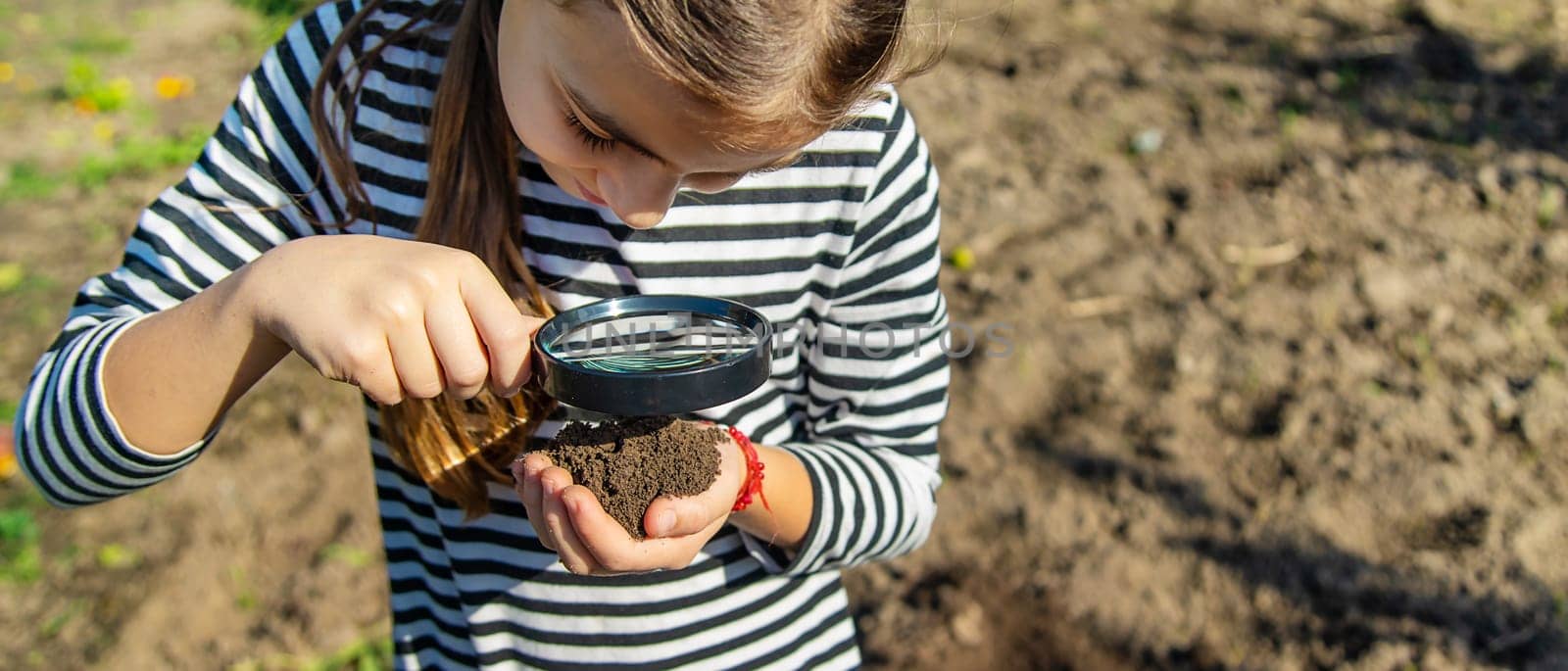 Children examine the soil with a magnifying glass. Selective focus. Kid.