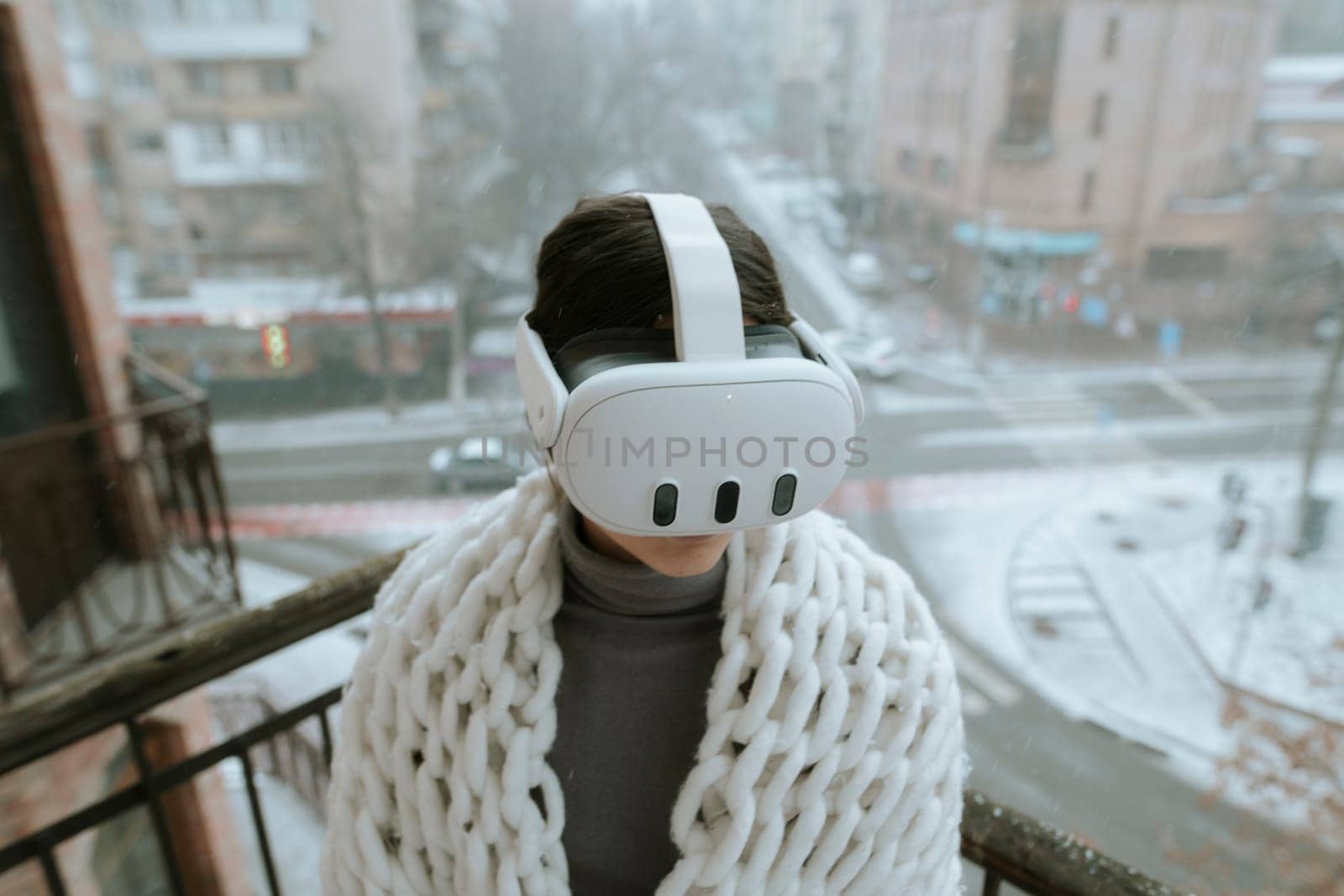 Winter chill meets virtual thrills as a young woman wears a VR headset on the balcony. by teksomolika