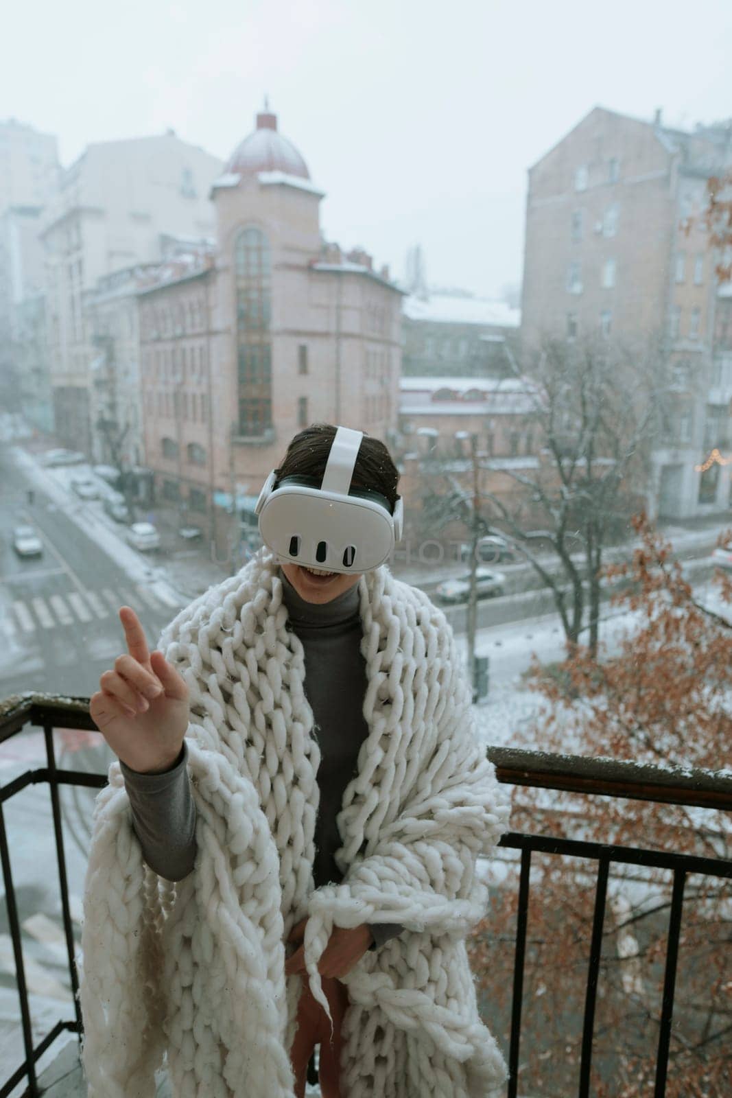 A girl stands on the balcony in winter, exploring virtual worlds with a VR headset. High quality photo
