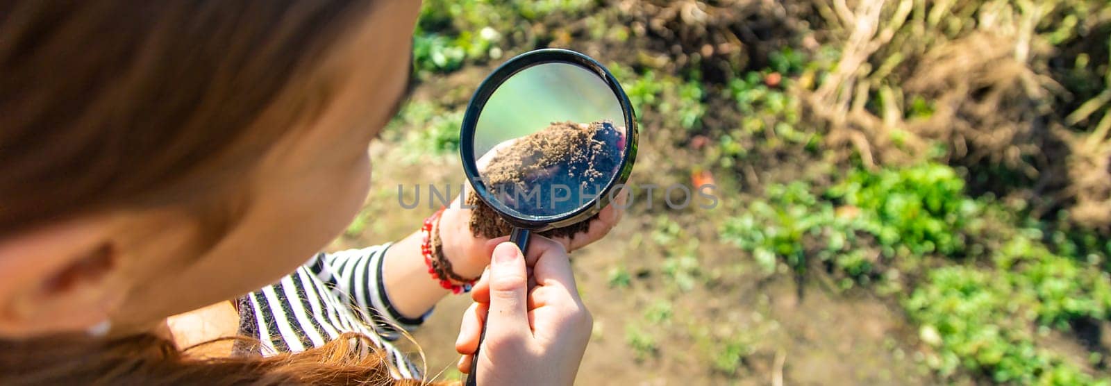 Children examine the soil with a magnifying glass. Selective focus. Kid.