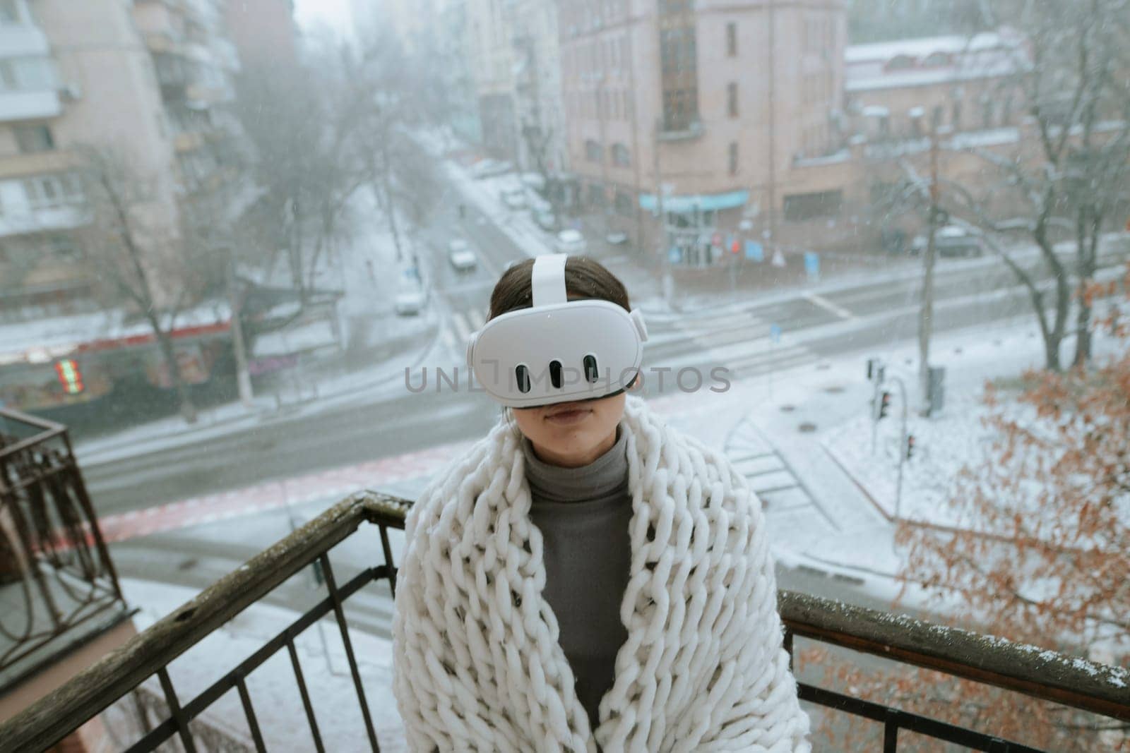 Enjoying VR experiences, a young lady dons a headset on the winter balcony. High quality photo
