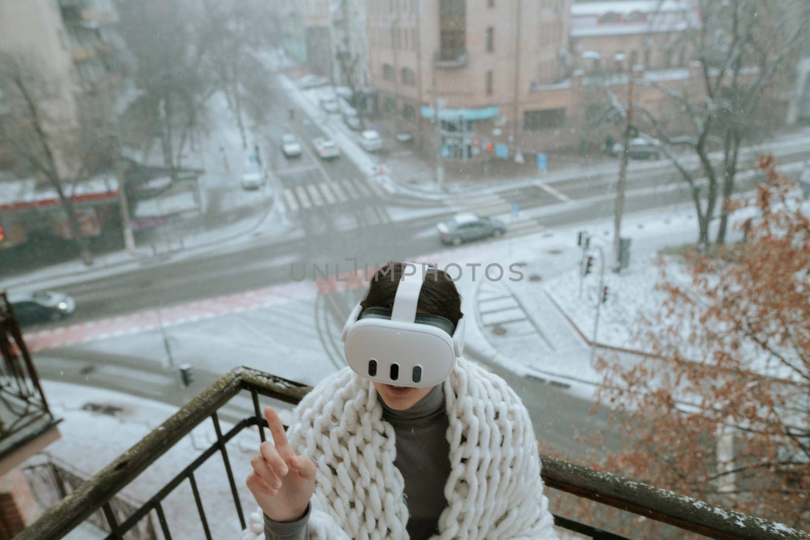 A young woman in a virtual reality headset stands on the balcony in winter. High quality photo