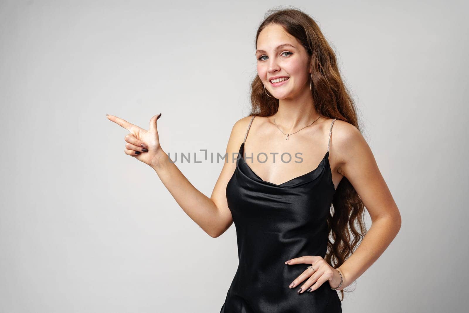 A woman wearing a black dress is pointing at an object or direction. She appears to be gesturing with determination or surprise.