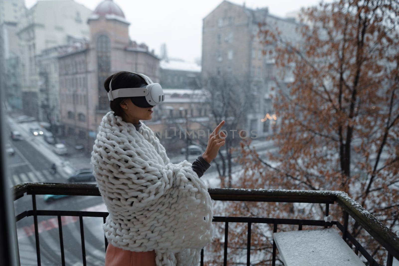 A radiant young woman enjoys the winter cityscape through her virtual reality glasses. by teksomolika