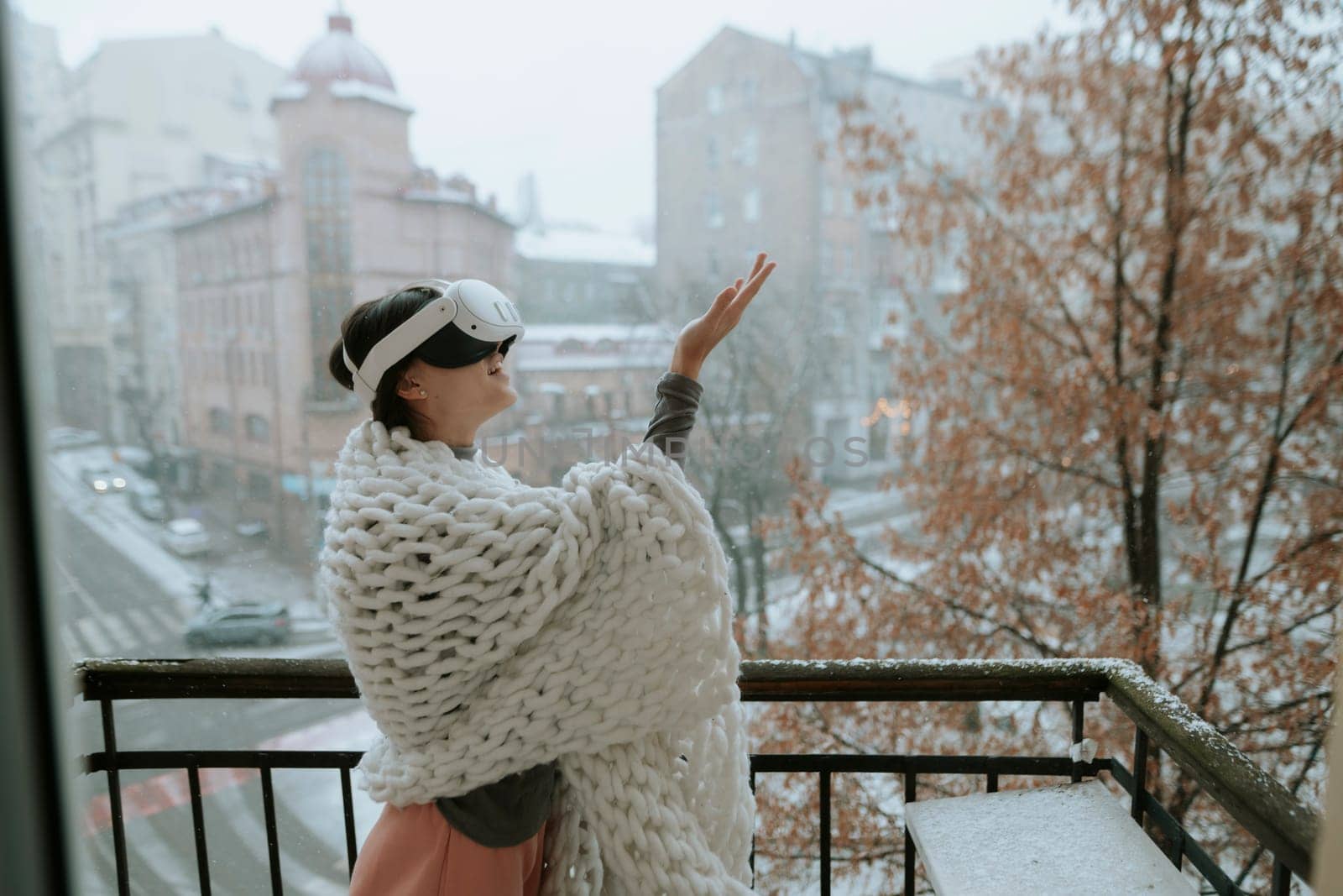 An enchanting woman in VR glasses gazes at the winter cityscape around her. High quality photo