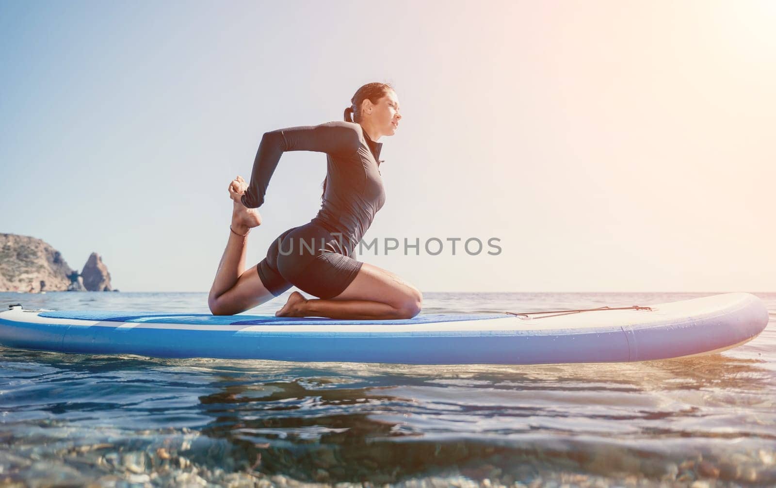 Woman sup yoga. Middle age sporty woman practising yoga pilates on paddle sup surfboard. Female stretching doing workout on sea water. Modern individual hipster outdoor summer sport activity