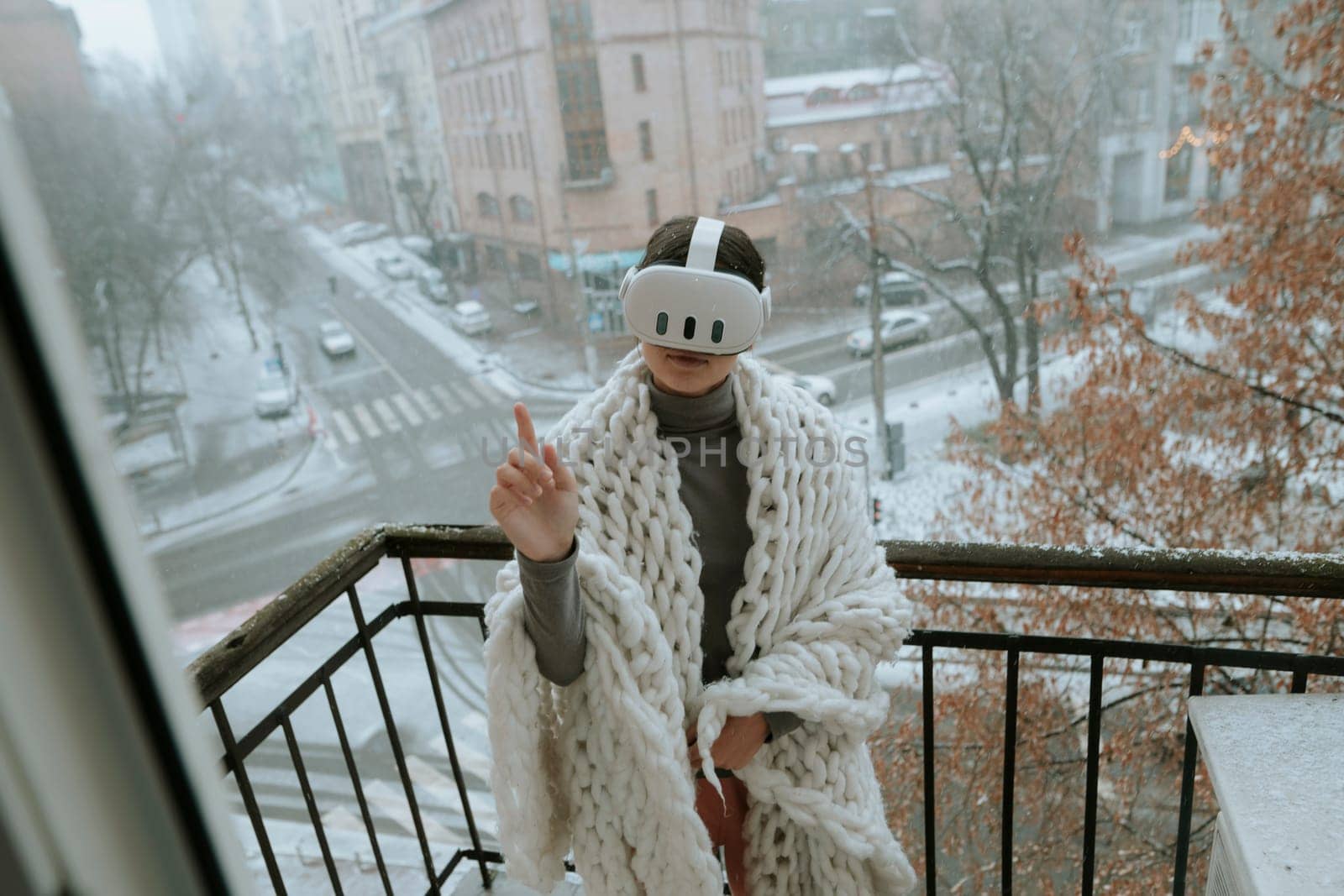 On the balcony in winter, a girl embraces virtual reality adventures with a headset. by teksomolika