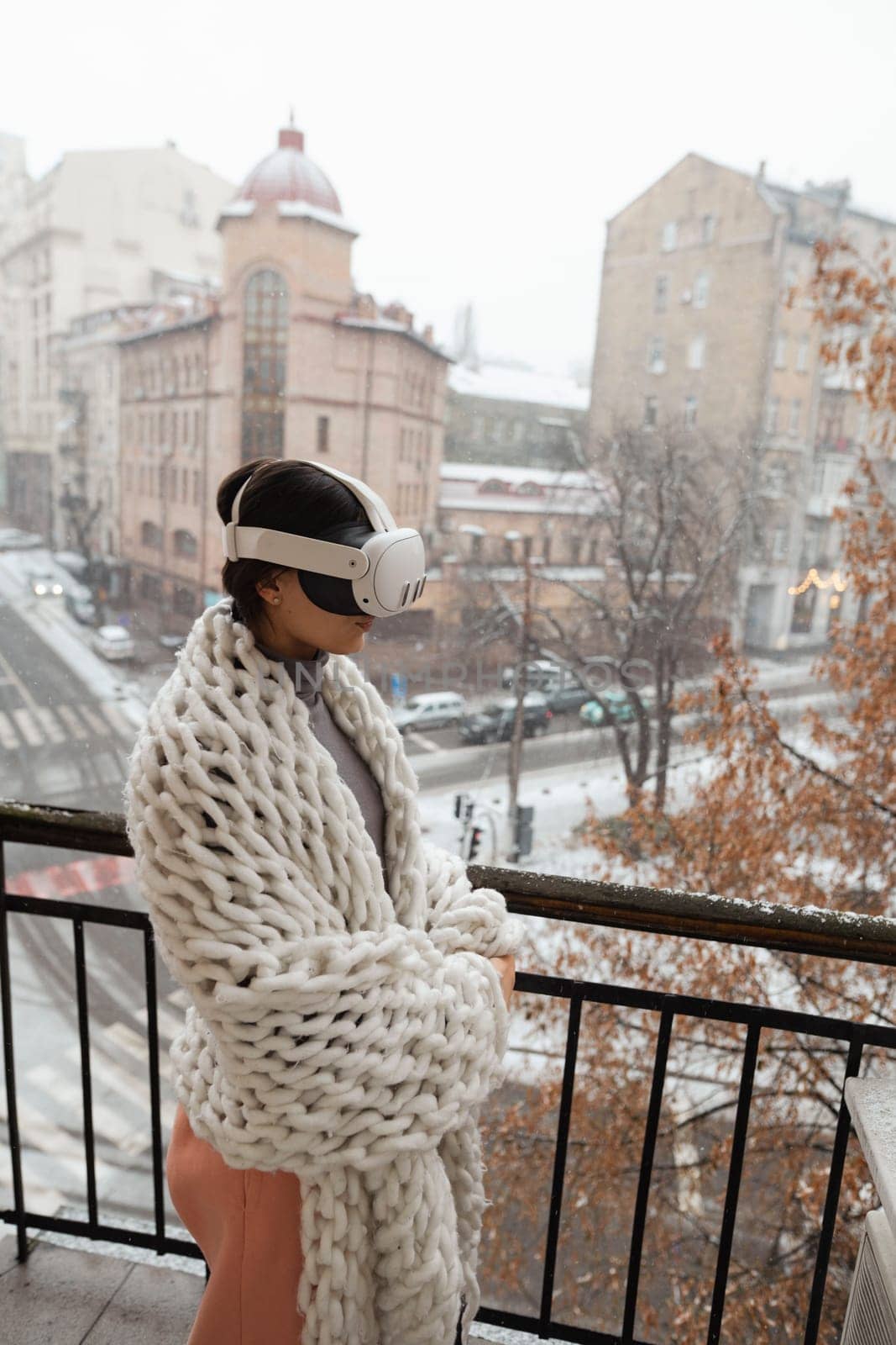 A stunning lady immersed in virtual reality stands amidst the winter city with VR glasses. High quality photo