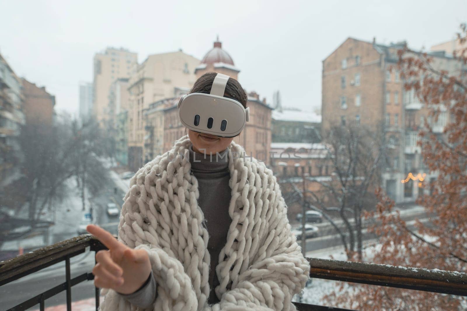 Enjoying VR experiences, a young lady dons a headset on the winter balcony. High quality photo