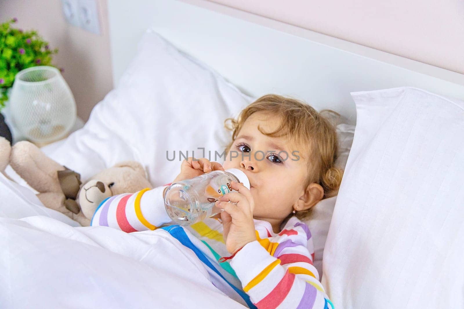 A child drinks from a bottle in bed. Selective focus. Kid.