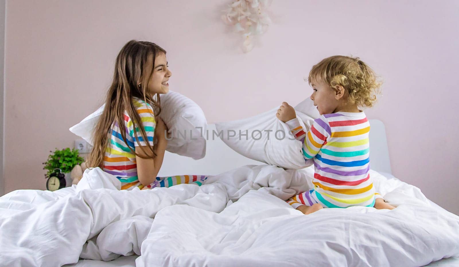 Children hitting pillows in bed. Selective focus. Kid.