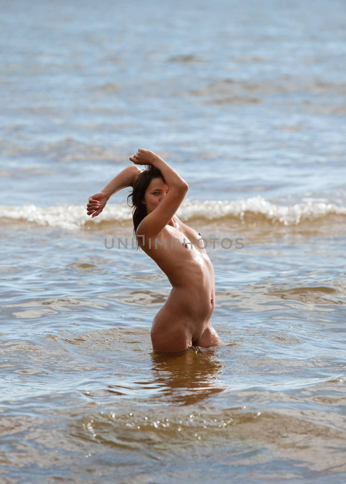 Young beautiful woman posing nude on the seaside enjoying the sea and nature