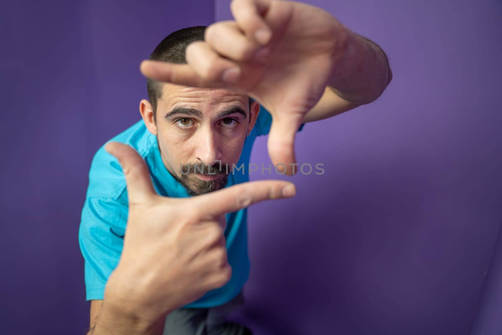 Man doing frame using hands and fingers, isolated over purple background. High quality photo