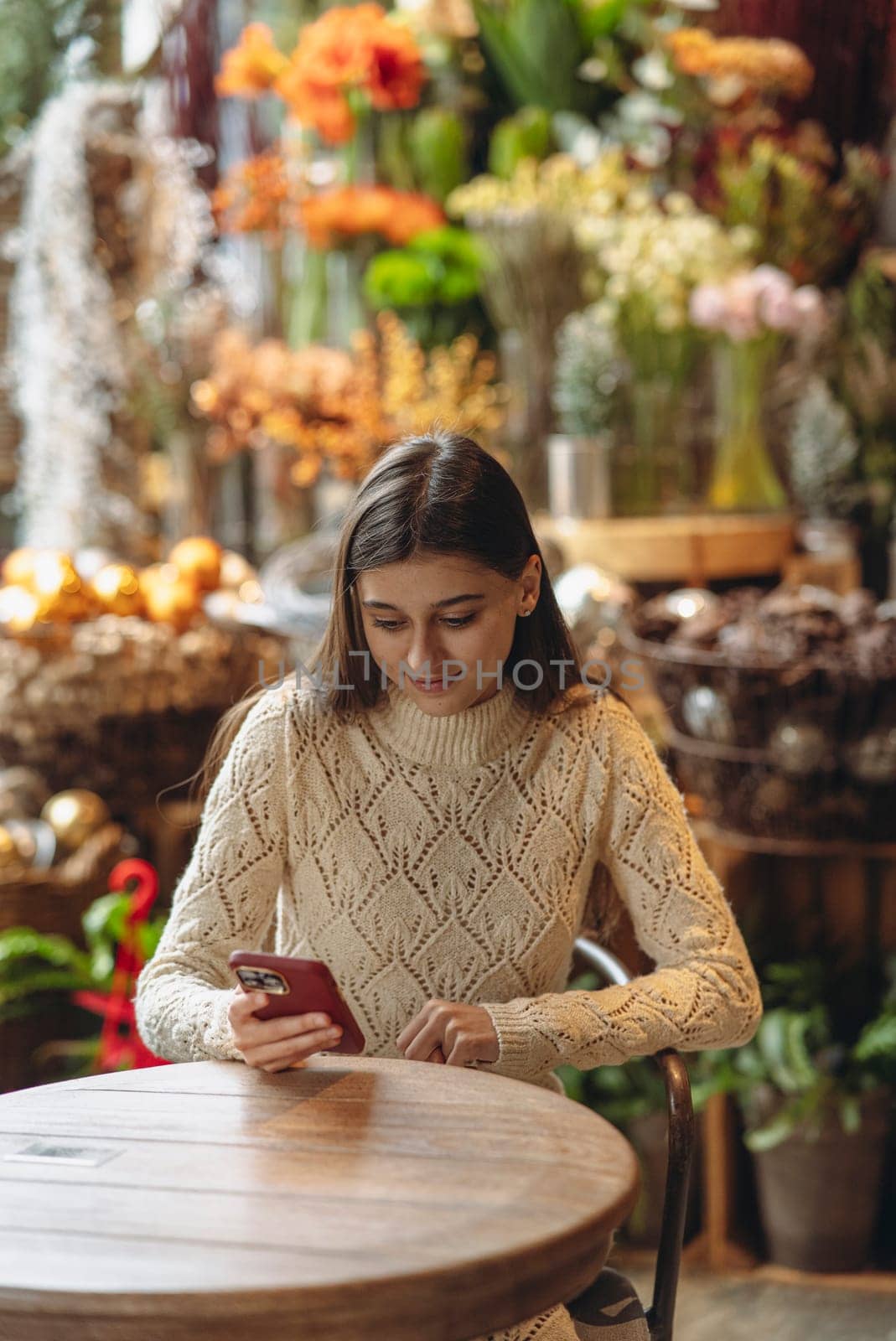 A gorgeous, bright young lady exploring holiday decorations while holding her smartphone. High quality photo