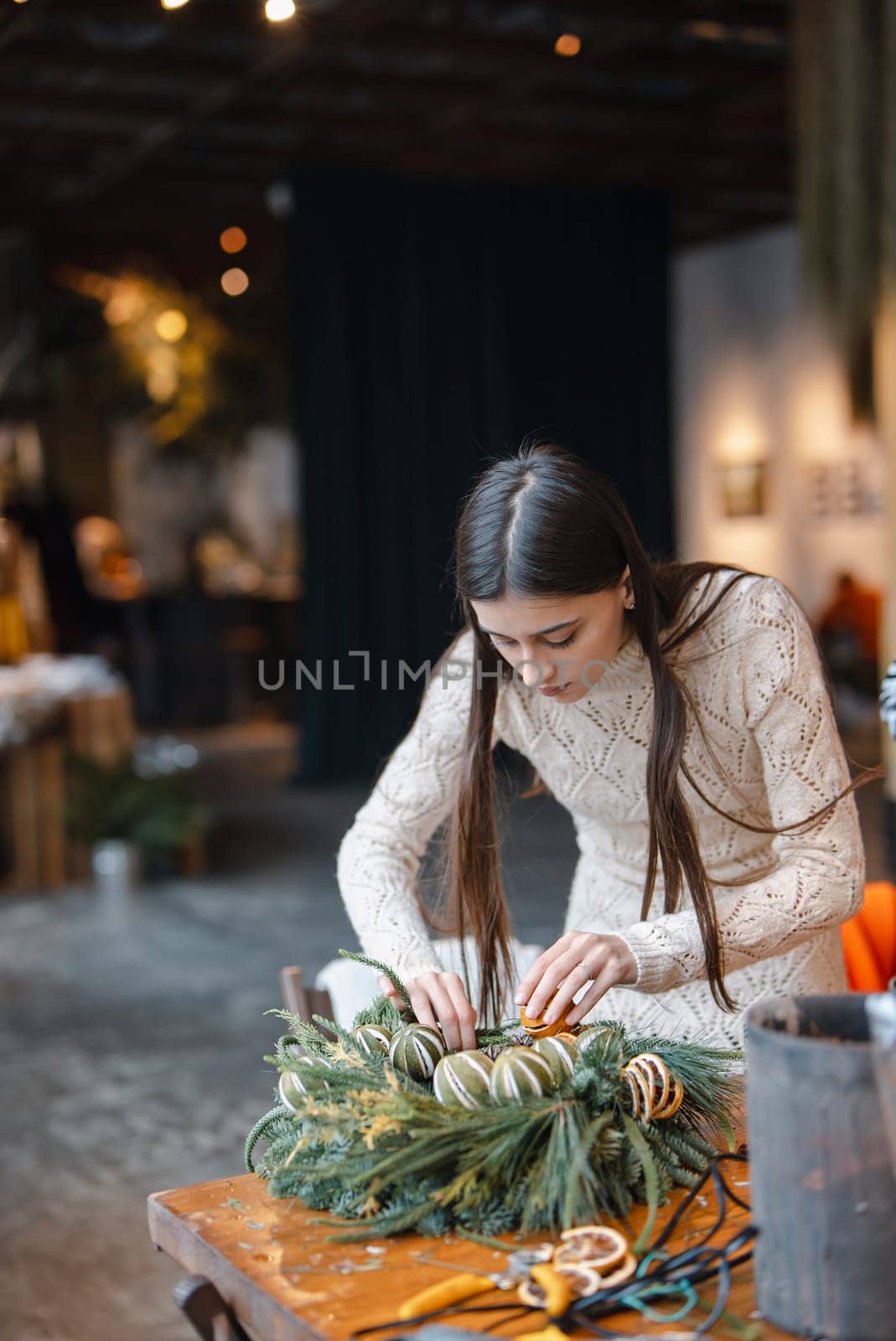 A stunning young lady deeply interested in a holiday decoration-making seminar. by teksomolika