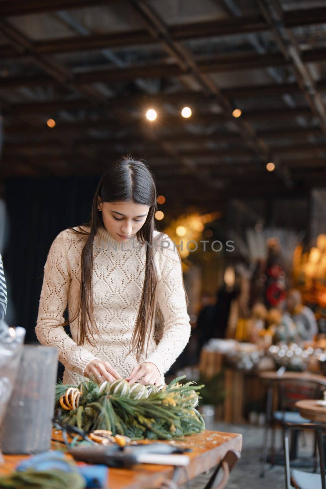 A charming young woman fully engaged in a Christmas decor crafting class. by teksomolika
