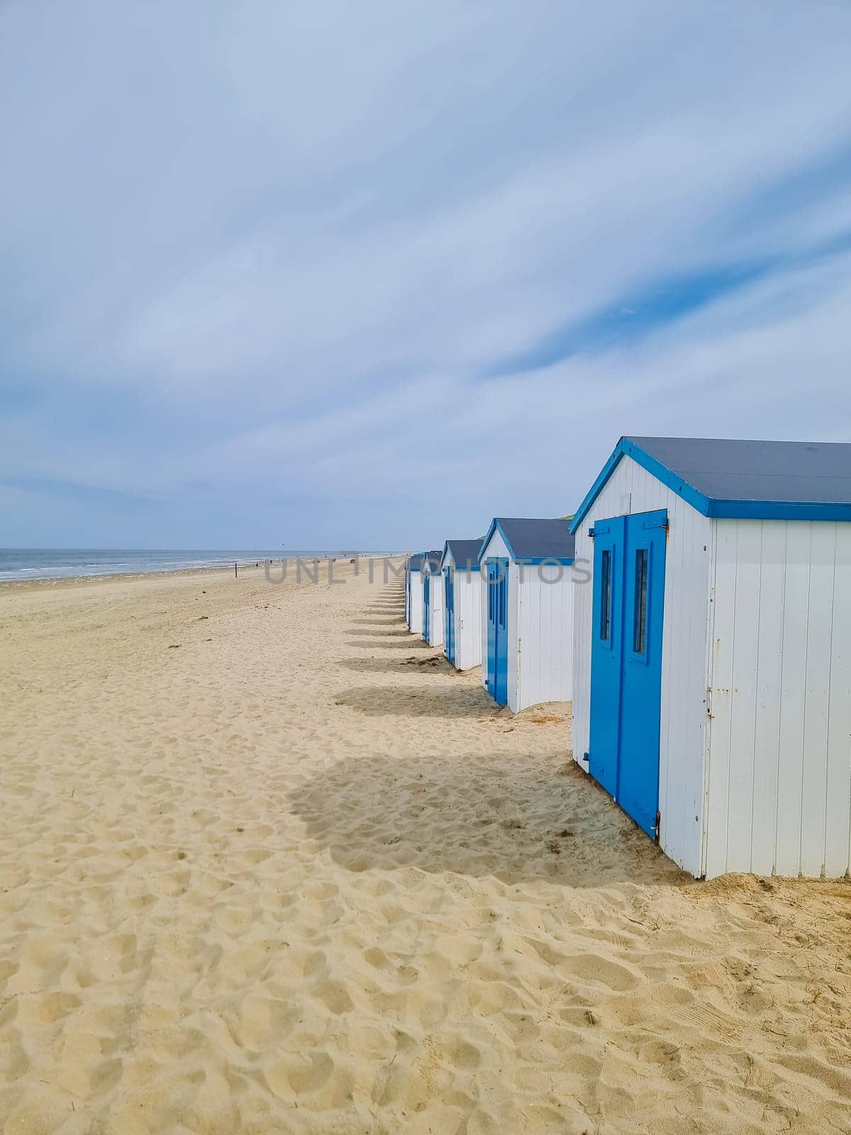 Colorful beach huts line the sandy shores of Texel in the Netherlands, creating a picturesque and serene scene by the sea.