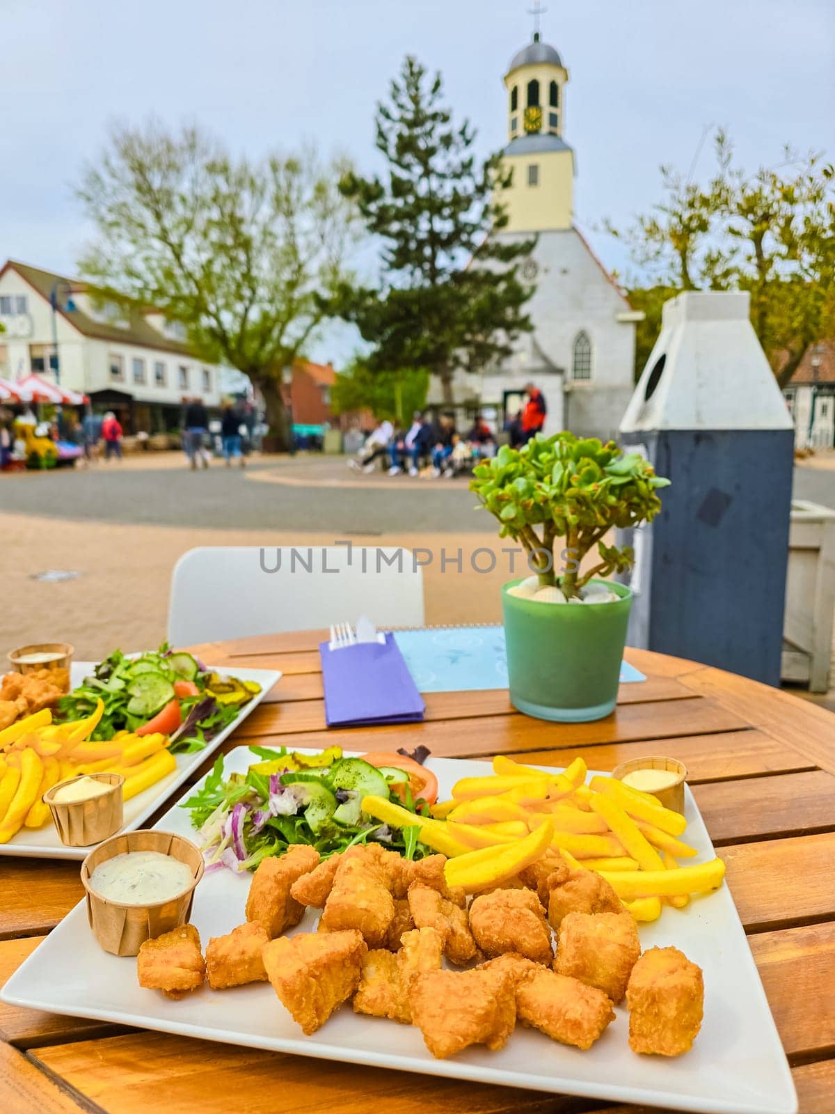 Two perfectly crispy plates of fish and chips, expertly presented on a rustic wooden table in Texel, Netherlands.