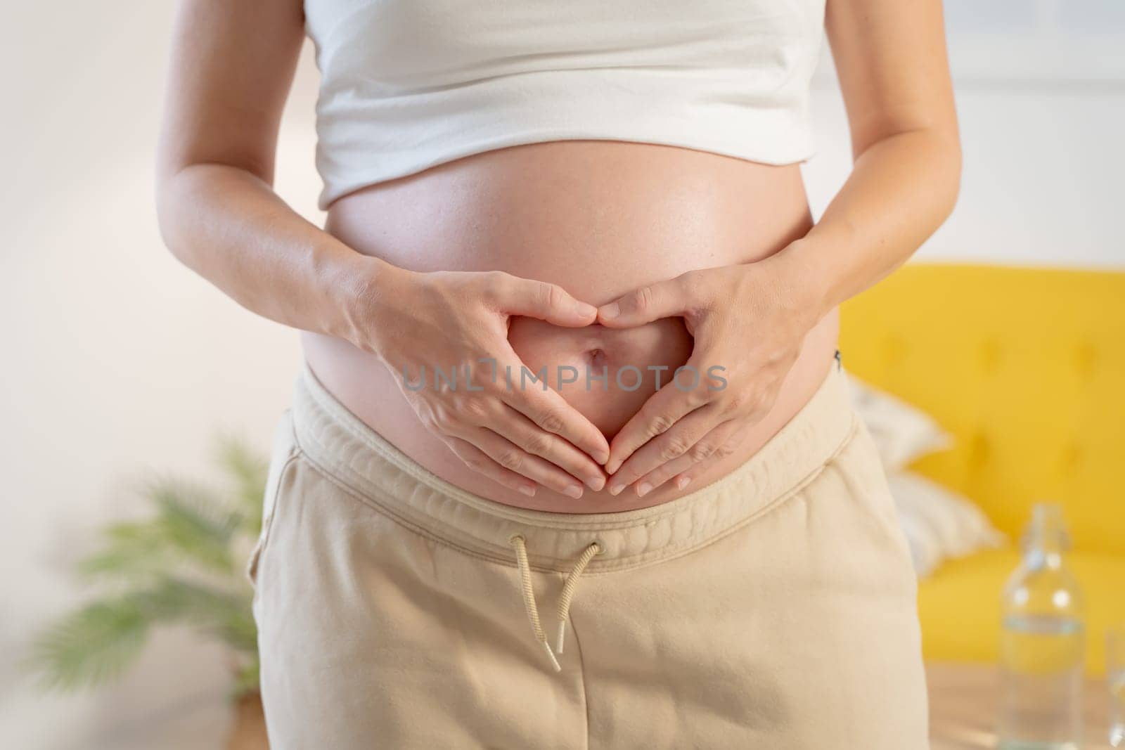 Pregnant woman loving her baby making a heart with his hands on his belly. High quality photo