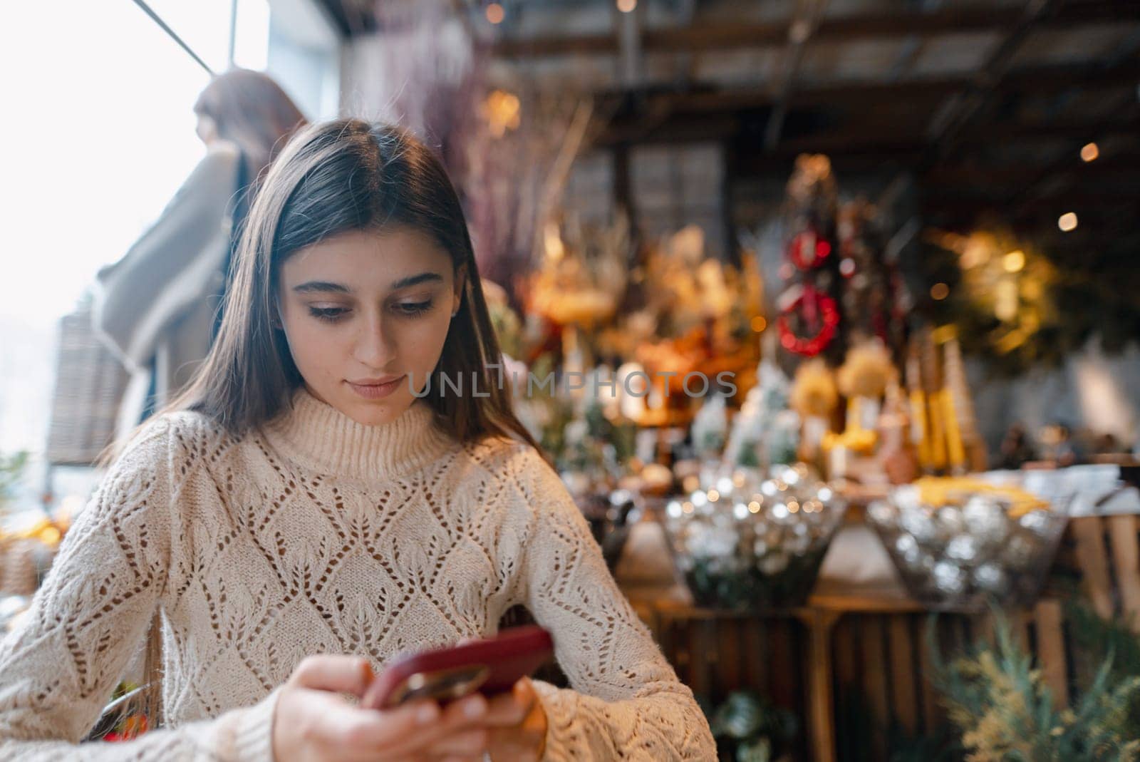 A striking, vibrant young woman checking out New Year's decorations with her smartphone. High quality photo