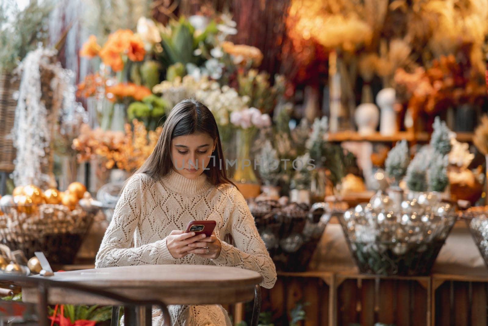 A stunning, colorful young woman browsing Christmas decorations with her smartphone. High quality photo