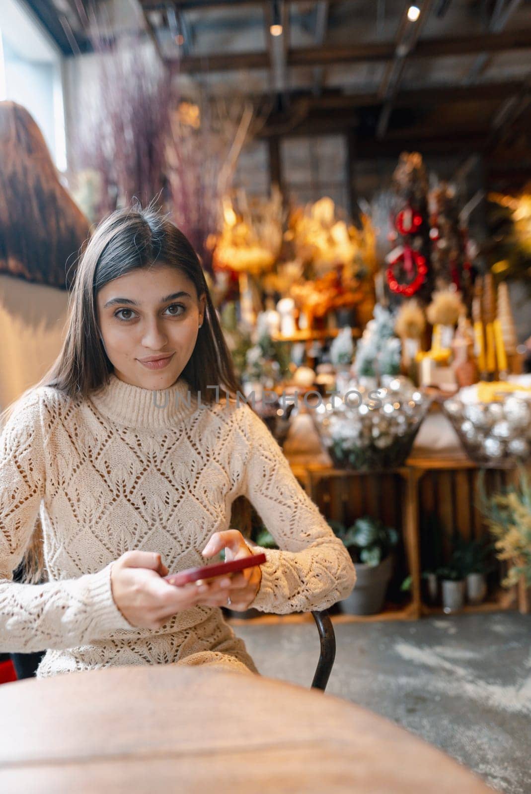 A stunning, colorful young woman browsing Christmas decorations with her smartphone. High quality photo