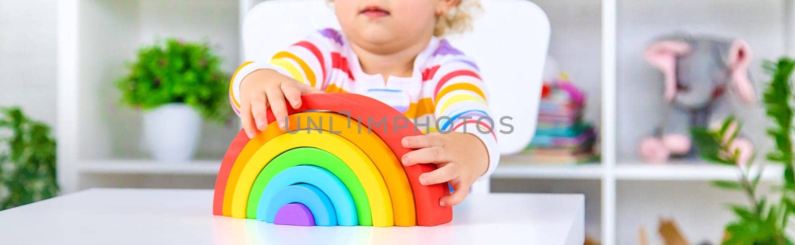 The child collects the constructor rainbow. Selective focus. Kid.