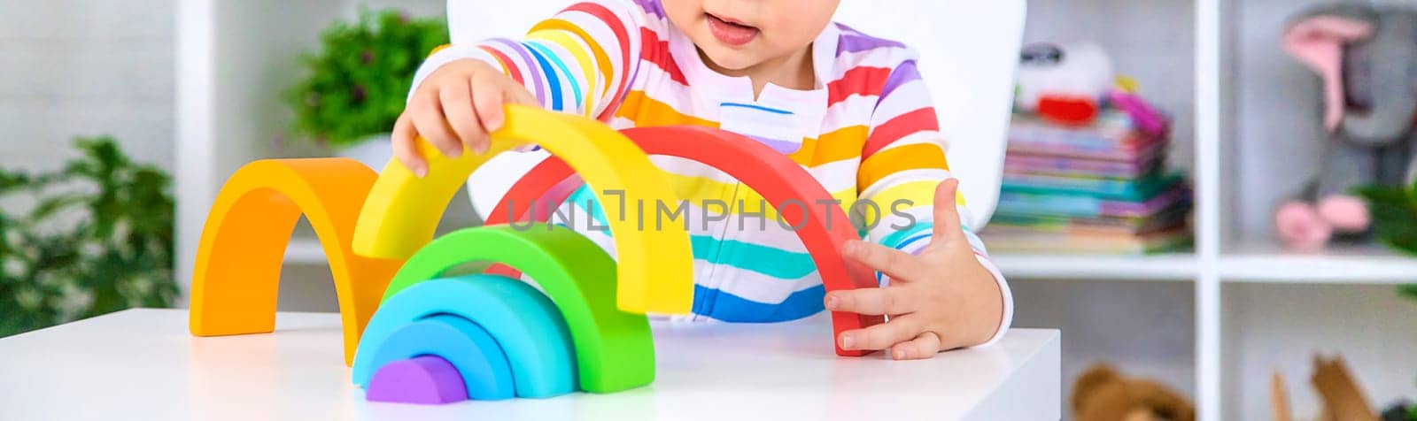 The child collects the constructor rainbow. Selective focus. Kid.