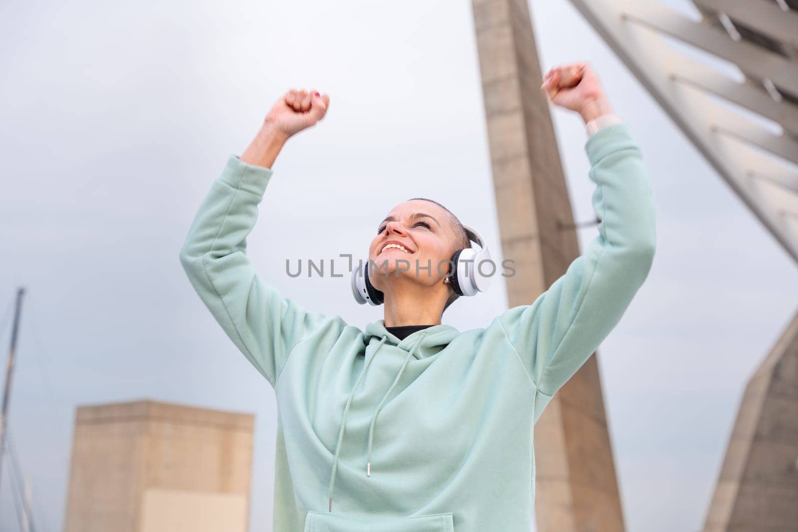 portrait sporty woman smiling with arms up outdoors. by mariaphoto3