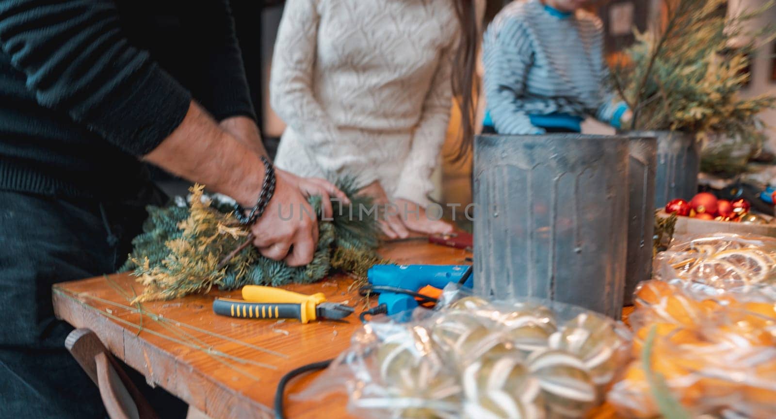 A young lady making a Christmas wreath at a DIY decor session. by teksomolika