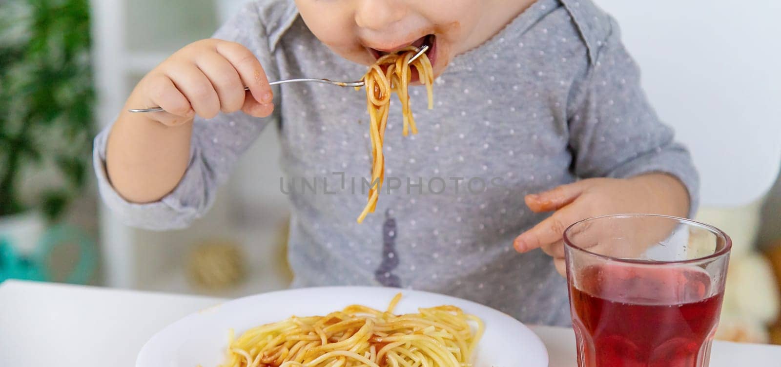 The child eats spaghetti lunch. Selective focus. Food.