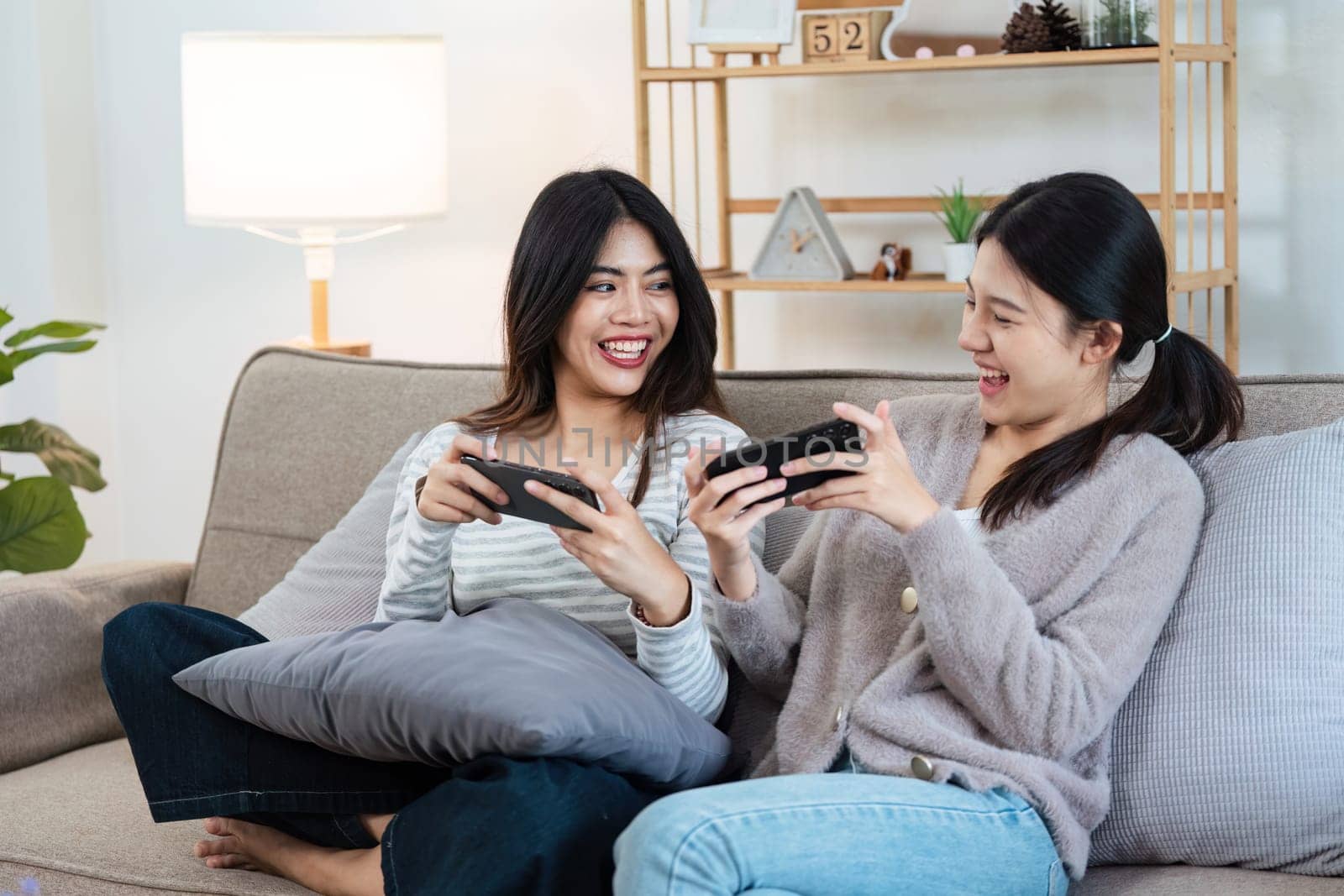 Happy woman lesbian gay lgbt couple enjoying fun gaming session on the couch at home.