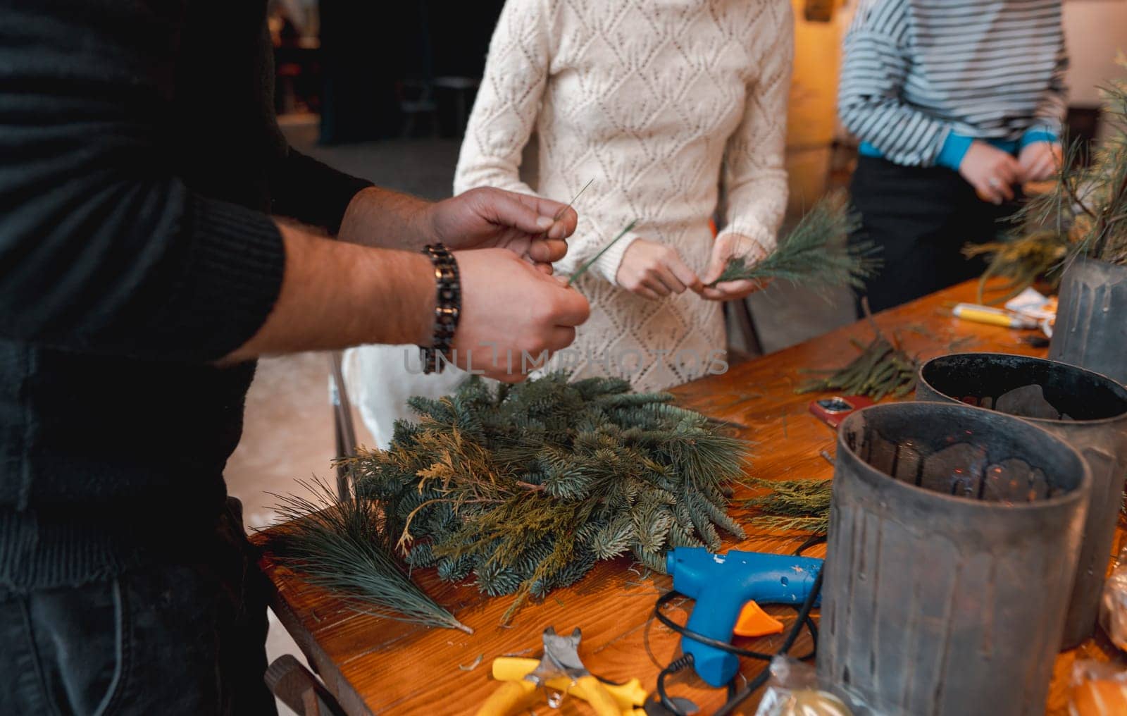 A young woman creating a Christmas wreath at a festive decoration workshop. by teksomolika