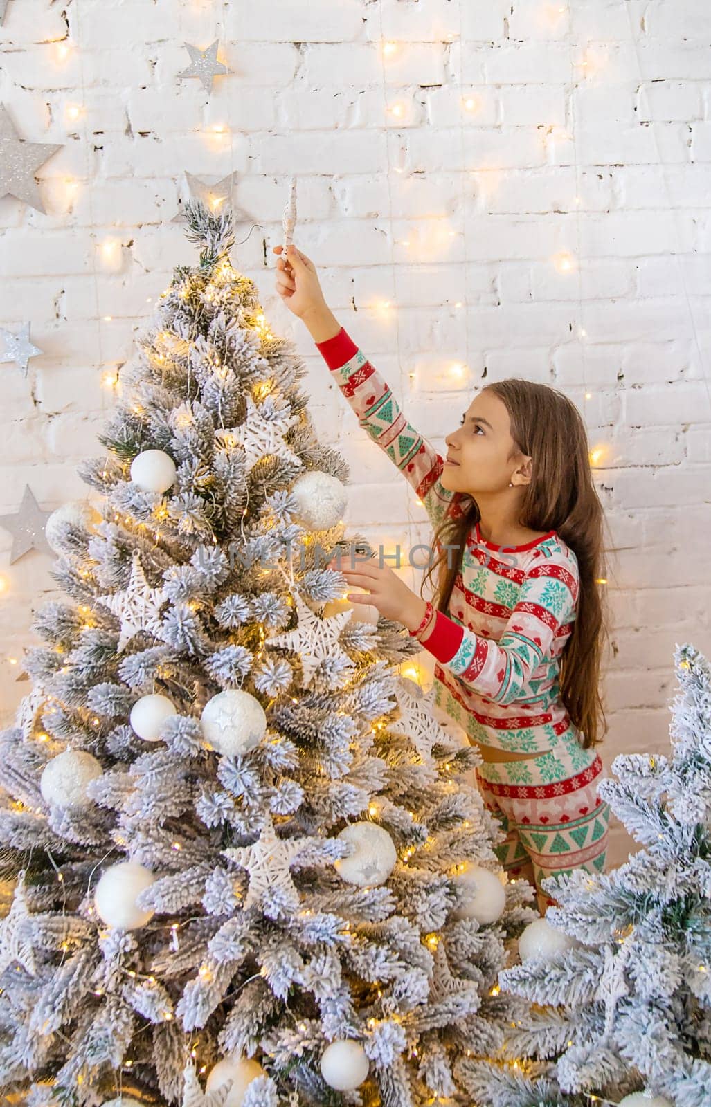 A child hangs a star on a Christmas tree. Selective focus. by yanadjana