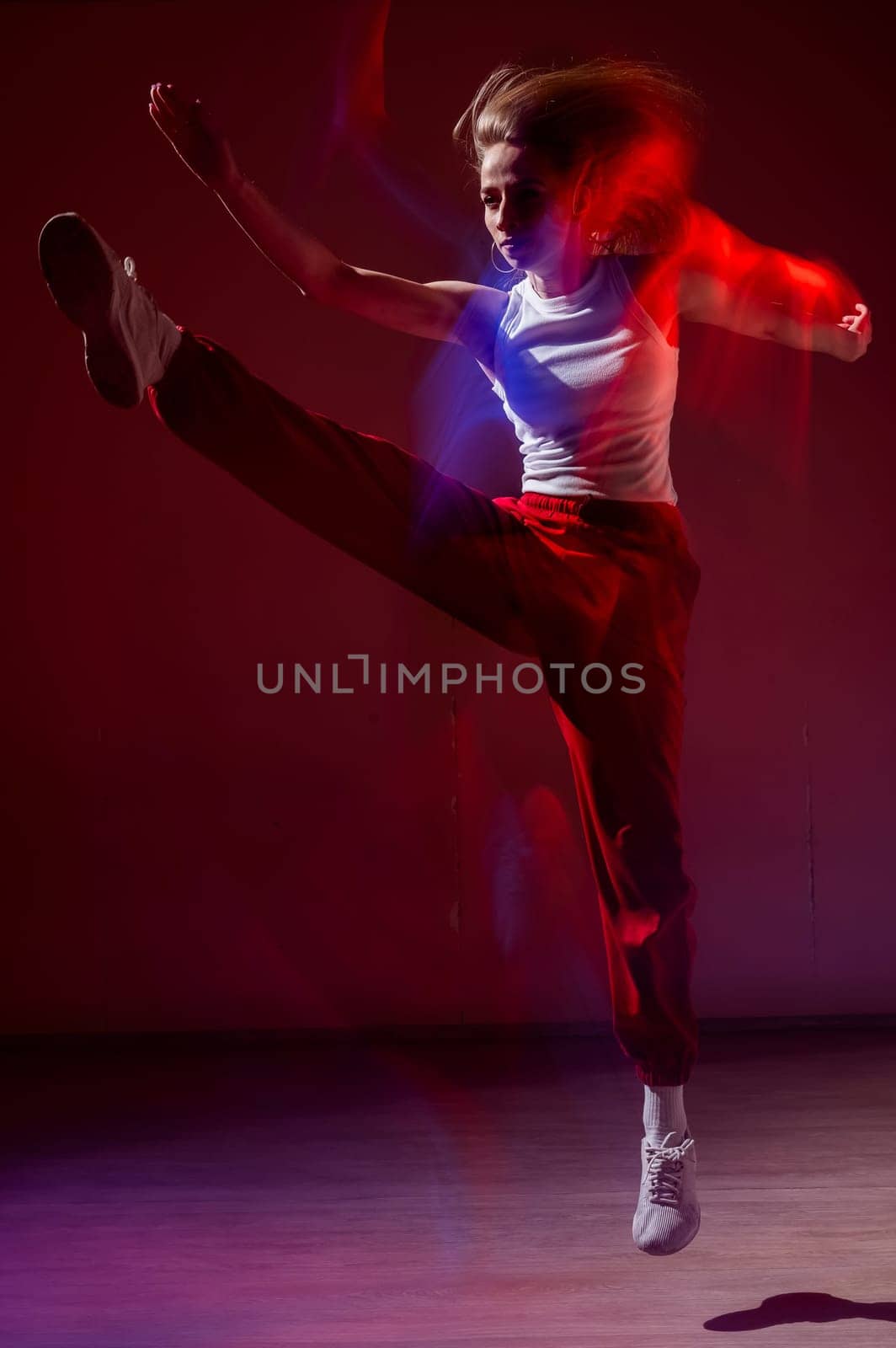 Young woman dancing modern dances in red blue neon light. Vertical photo