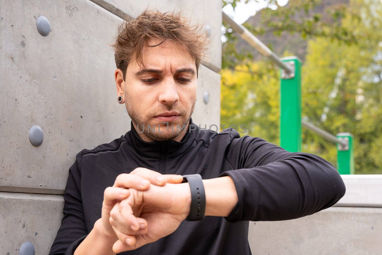 Sportsman looking at smartwatch with blank screen outdoors. by mariaphoto3