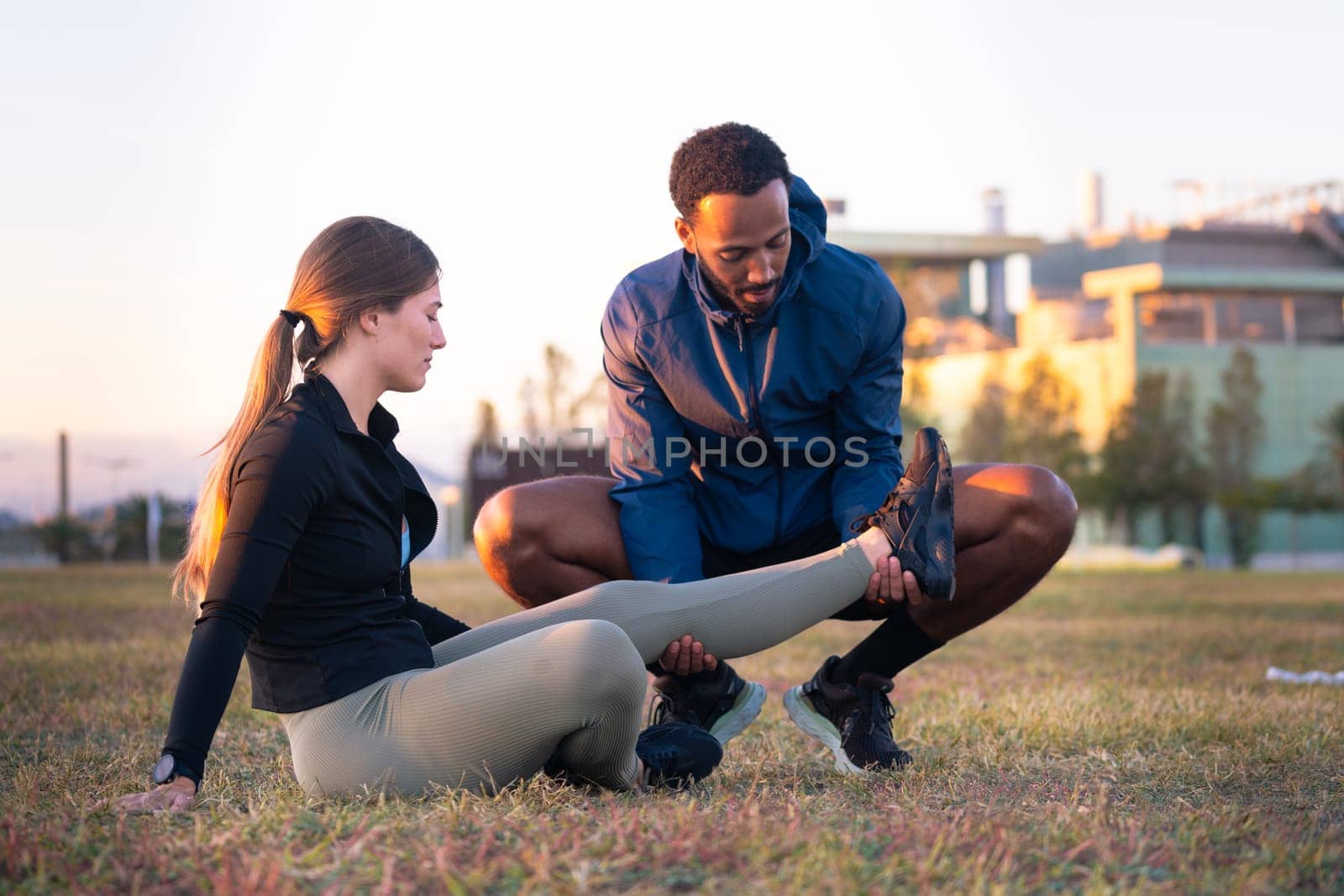 A young woman receives first aid after suffering an accident while running. Athlete Injured Leg Seen by Physical Therapist