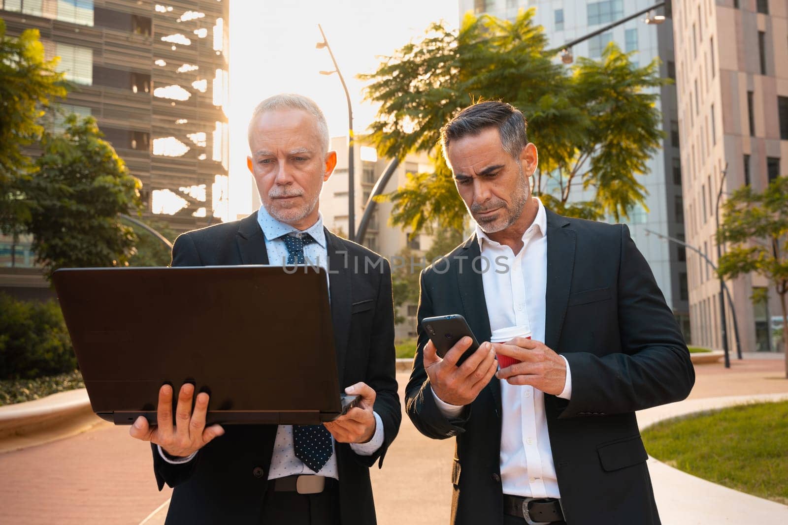 Two trusted business colleagues dressed in formal attire with a computer in hand observing the results of the work done